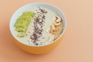 Smoothie bowl with kiwifruit, cashew nuts, chia seeds beige background
