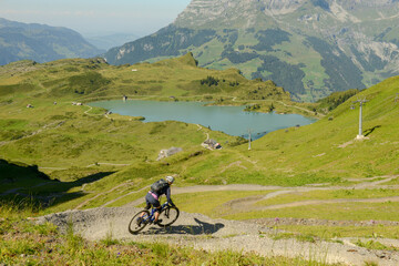 Man on mountain bike going down the flow track from Jochpass over Engelberg in the Swiss Alps