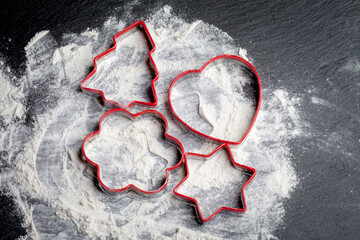 spruce-shaped metal cookie cutter. form for cutting dough on a background of flour on a black marble board