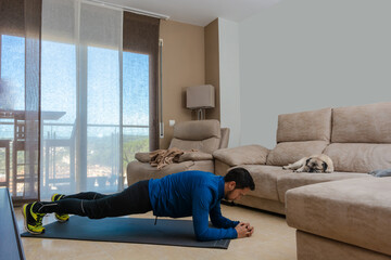 Latin man, doing a workout in his living room.