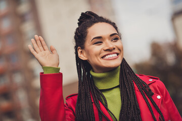 Photo of young cheerful afro woman happy positive smile walk city street wave hand hello hi look empty space © deagreez