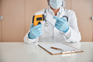 Male doctor demonstarting a modern contactless thermometer