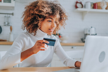 Lady with perfect dark skin holding credit card and inserting bank information for online shopping...