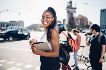 Smiling black female student using tablet on street