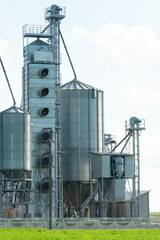 Obraz premium silver silos on agro manufacturing plant for processing drying cleaning and storage of agricultural products, flour, cereals and grain. Large iron barrels of grain. Granary elevator