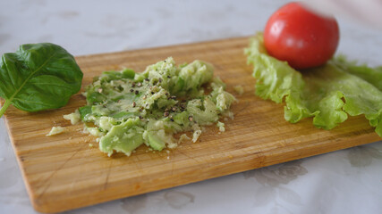 Peppering of mashing avocado with black pepper on a board. Healthy food cooking