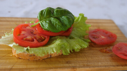 Fototapeta na wymiar Finishing Homemade nutrition breakfast with sandwich, lettuce leaf, tomato