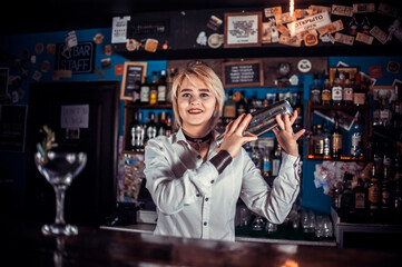 Experienced girl bartending demonstrates his skills over the counter while standing near the bar counter in bar