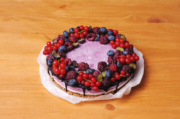 Festive cake, blueberry and blackberry sponge cake with cream cheese inside on a plate on a wooden table, horizontal view from above.