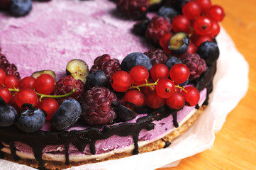 Festive cake, blueberry and blackberry sponge cake with cream cheese inside on a plate on a wooden table, horizontal view from above.Macro photo.