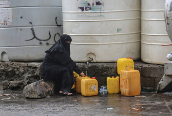 Yemeni woman collects water in the Yemeni city of Taiz