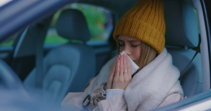 Unhealthy girl young sick woman sitting in car suffering fever allergy sneezing into paper tissue commuting to work. Coronavirus outbreak. Pandemic. Healthcare concept.