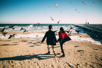 lovers run on the beach in winter chasing pigeons after quarantine