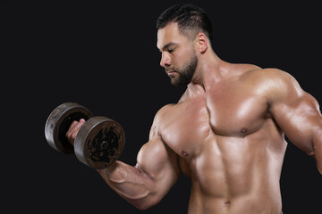 Fototapeta na wymiar A handsome beefy man is focused on performing the exercise lifting a dumbbell with one hand isolated on black background