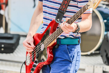 White guy playing colourful guitar outside on a sunny day
