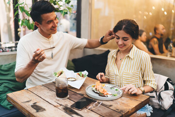 Beautiful diverse couple in love flirting in cafeteria while eating together