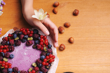 Festive cake, blueberry and blackberry sponge cake with cream cheese inside on a plate on a wooden table, horizontal view from above.
