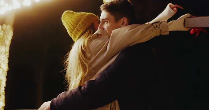 Happy boyfriend making surprise to his woman celebrating romantic anniversary together sharing presents hugging and swinging outdoors. Love couple. Dating concept.