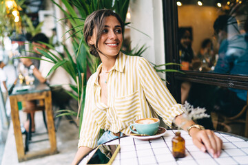 Positive woman sitting in open cafe