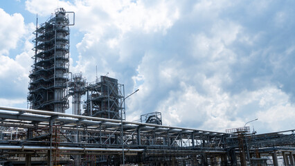 Distillation tower or column on blue sky with clouds background. Oil refinery plant. Refining complex. Petrochemical industry concept.