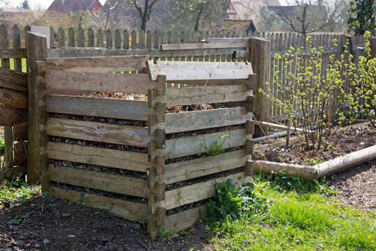 Alter Komposter aus Holz mit Komposthaufen im Garten