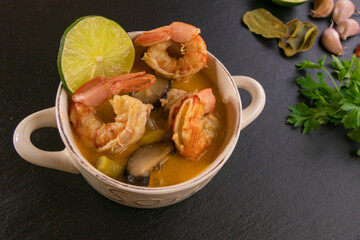 Bowl of spicy Thai Tom Yum Soup on slate.