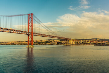 Looking back at the 25th of April bridge in Lisbon, Portugal from the river Tagus in the early morning light at sunrise in Autumn