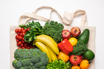 Cotton bag full of vegetables and fruits. Closeup shopping bag on white background. Zero waste buying