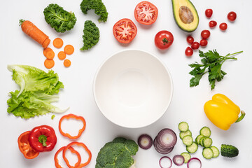 Creative layout made of variety of vegetables for making salads. Carrots, lettuce, kale, tomato, cucumber, broccoli, avocado, red bell pepper, onion.  White background, top view, copy space