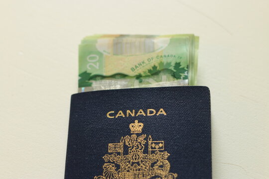 Canadian passport laying on top of twenty dollar bills. Concept of immigrating or emigrating, or travelling with a canadian passport