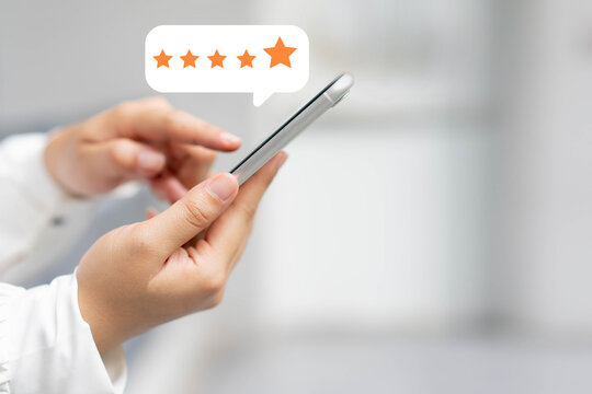 close up on customer woman hand pressing on smartphone screen with gold five star rating feedback icon and press level three rank (good) for give score point to review the service business concept	