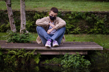 Fototapeta premium sad boy with mask looking at the pond
