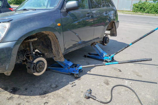 Car on two jacks with wheels removed. Seasonal wheel replacement.