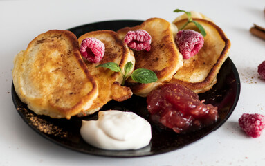 Breakfast with pancakes on plates, sour cream and pavidl. Pancakes are on a white table and the guy is holding in his hands.