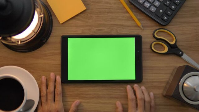 Top view of woman use digital tablet with green screen. Office desk background. Chroma key. Tablet with green screen in table
