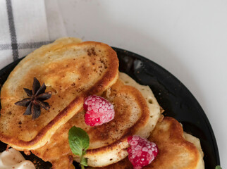 Breakfast with pancakes on plates, sour cream and pavidl. Pancakes are on a white table and the guy is holding in his hands.