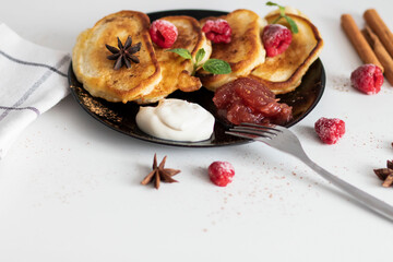 Breakfast with pancakes on plates, sour cream and pavidl. Pancakes are on a white table and the guy is holding in his hands.