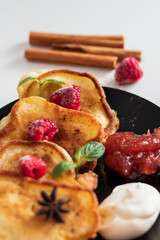 Breakfast with pancakes on plates, sour cream and pavidl. Pancakes are on a white table and the guy is holding in his hands.