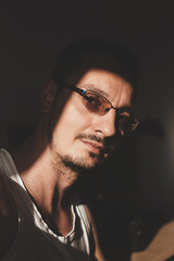 Dramatic light indoor portrait of young man wearing eyeglasses with transition (photo sensitive) lenses