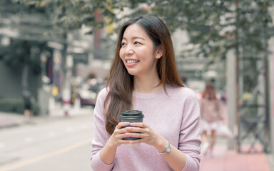 Woman drinking coffee while walking beside street