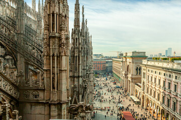 Naklejka premium Roof of Milan Cathedral Duomo di Milano with Gothic spires and white marble statues. Top tourist attraction on piazza in Milan, Lombardia, Italy. Wide angle view of old Gothic architecture and art.