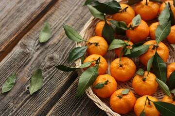 Juicy tangerines with green leaves on a wooden table 