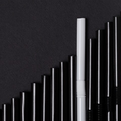 Group black cocktail straws straw on dark background. Individuality concept.