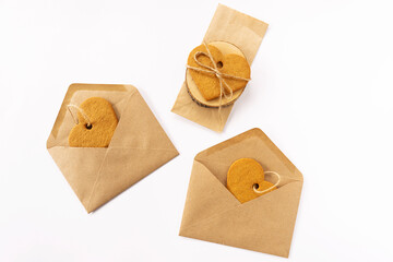 Handemade cookies in the shape of the heart lie on a crafted paper envelopes. St. Valentine’s day