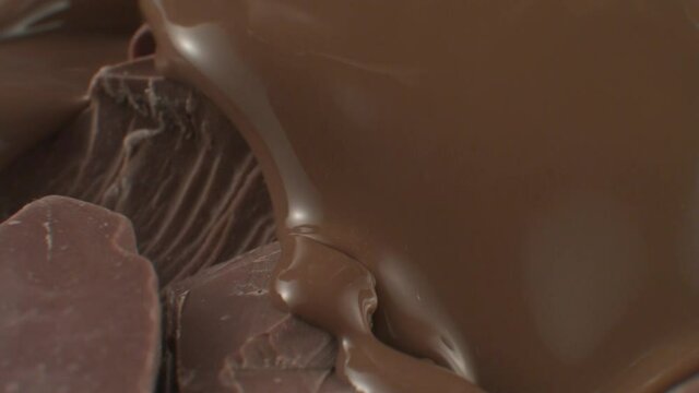 Close-up rotational motion melted chocolate is poured into pieces of large lumpy chocolate. The concept of exquisite taste. The concept of desserts and restaurant dishes