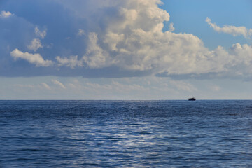 Obraz premium a fishing boat in the middle of the sea in the clouds on a beautiful autumn day