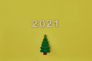 Toy tree and inscription 2021 on yellow background. New Year's decor. Copy space, mock up.