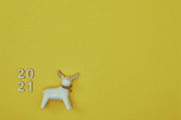 Glass toy deer and the inscription 2021 on a yellow background. Copy space, mock up