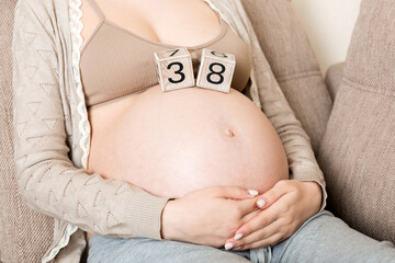 Pregnant woman in white underwear on bed in home holding calendar with weeks 38 of pregnant....