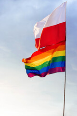 Polska oraz tęczowa flaga z barwami LGBT na tle niebieskiego nieba z białymi chmurami © Mikołaj Rychter